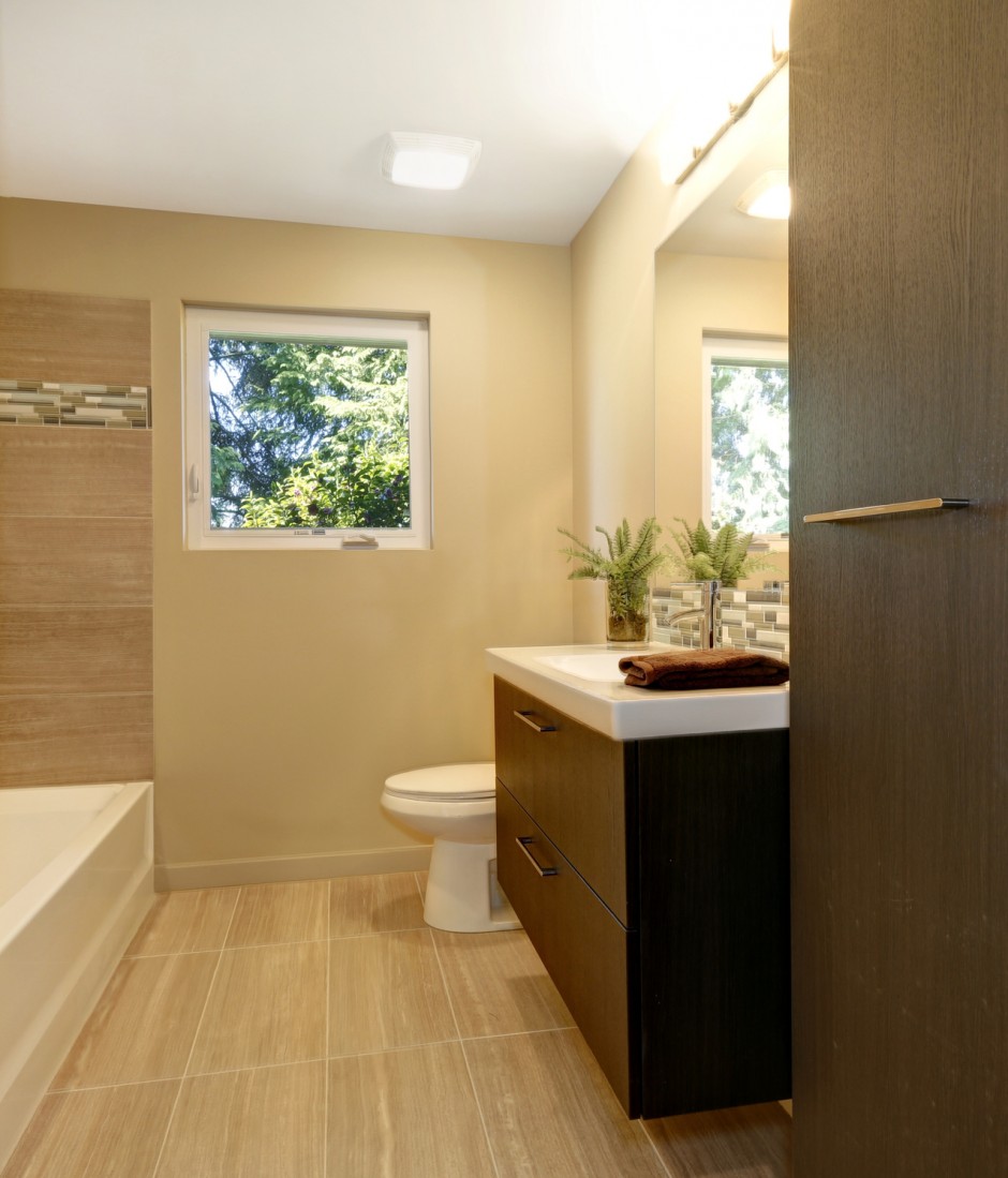 Beige modern new bathroom with brown wood cabinets and tub.